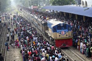 epa03910372 Homebound people crowd on the roof of a train as an attempt to travel to their villages, ahead of the Eid Al-Adha celebrations, at the Airport Railway Station in Dhaka, Bangladesh, 15 October 2013. Millions of people travel back to their villages to celebrate the big festival, Eid Al-Adha. EPA/ABIR ABDULLAH