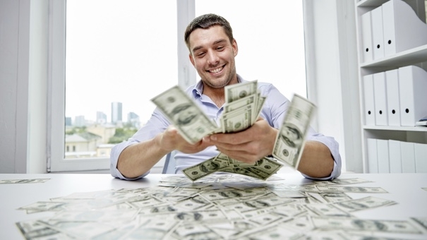 business, people, success and fortune concept - happy businessman with heap of dollar money in office