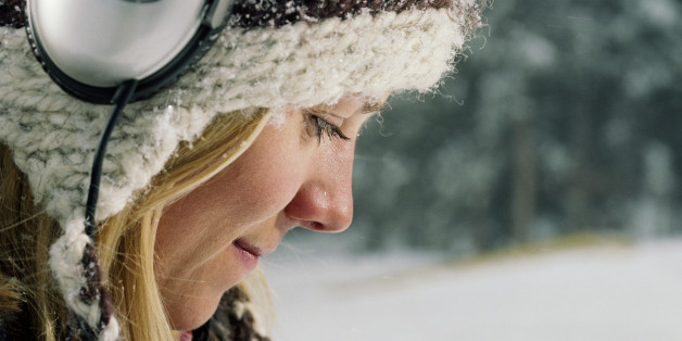 Young woman wearing knit cap and headphones, side view