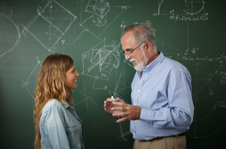 Teacher talking with young student in the classroom