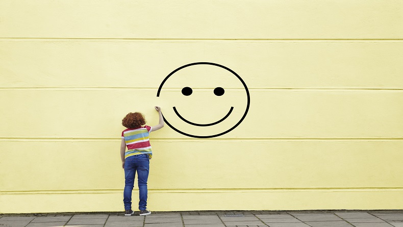 Girl drawing smiley face on to a wall