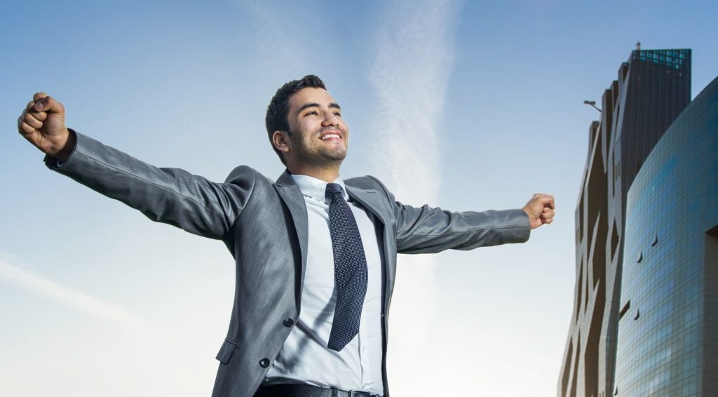 Successful businessman with his arms wide open. Joyous man with success perspective, modern buildings at background