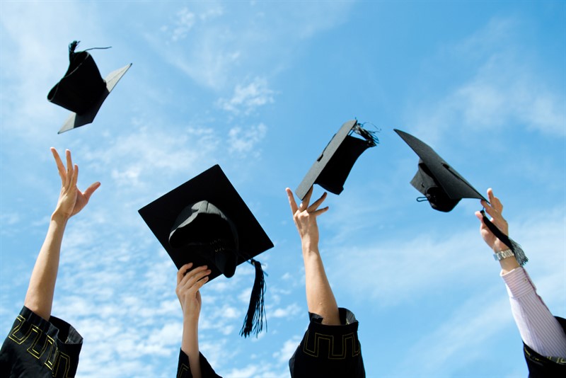 graduates throwing graduation hats in the air.