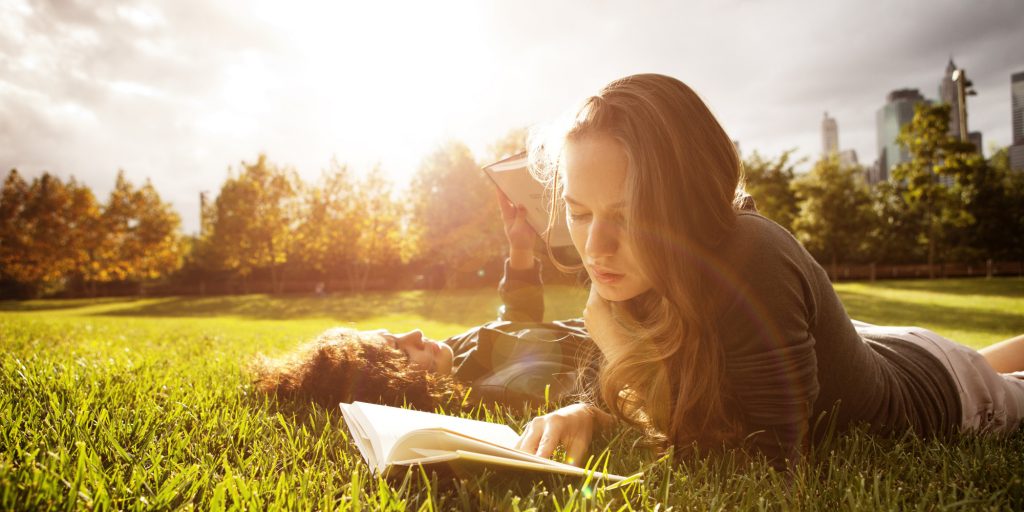 Two Young Women Readin In Park At Sunset