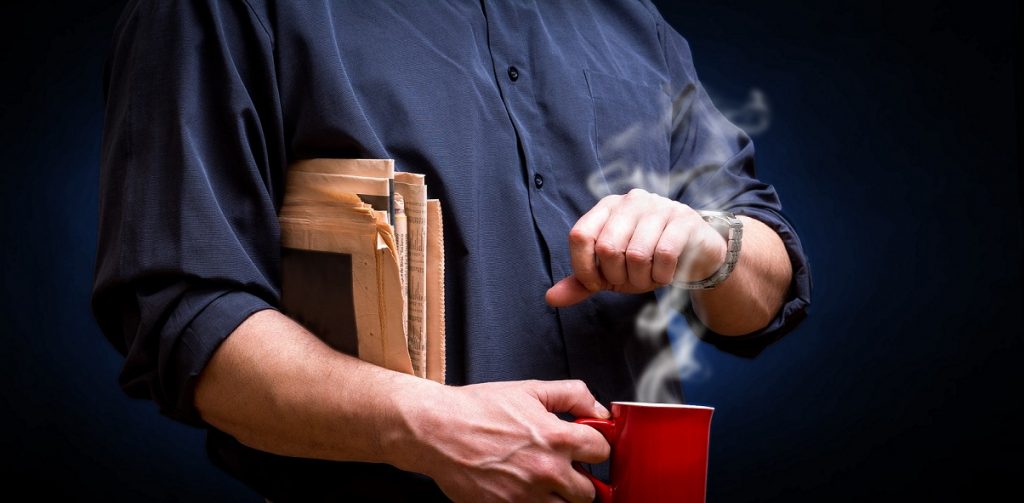 Business man with newspaper drinking hot coffee and looking watch