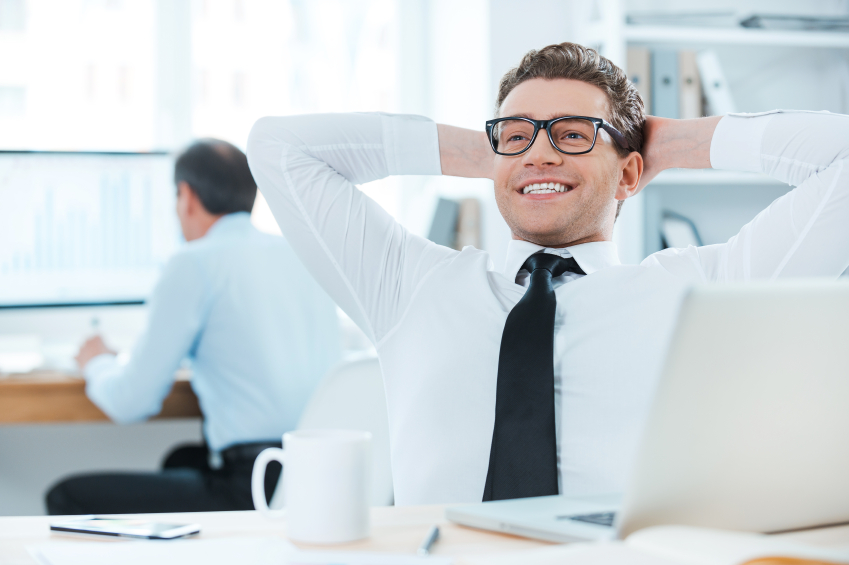 Satisfied with the work done. Cheerful businessman in formalwear holding head in hands while sitting at his desk in the office